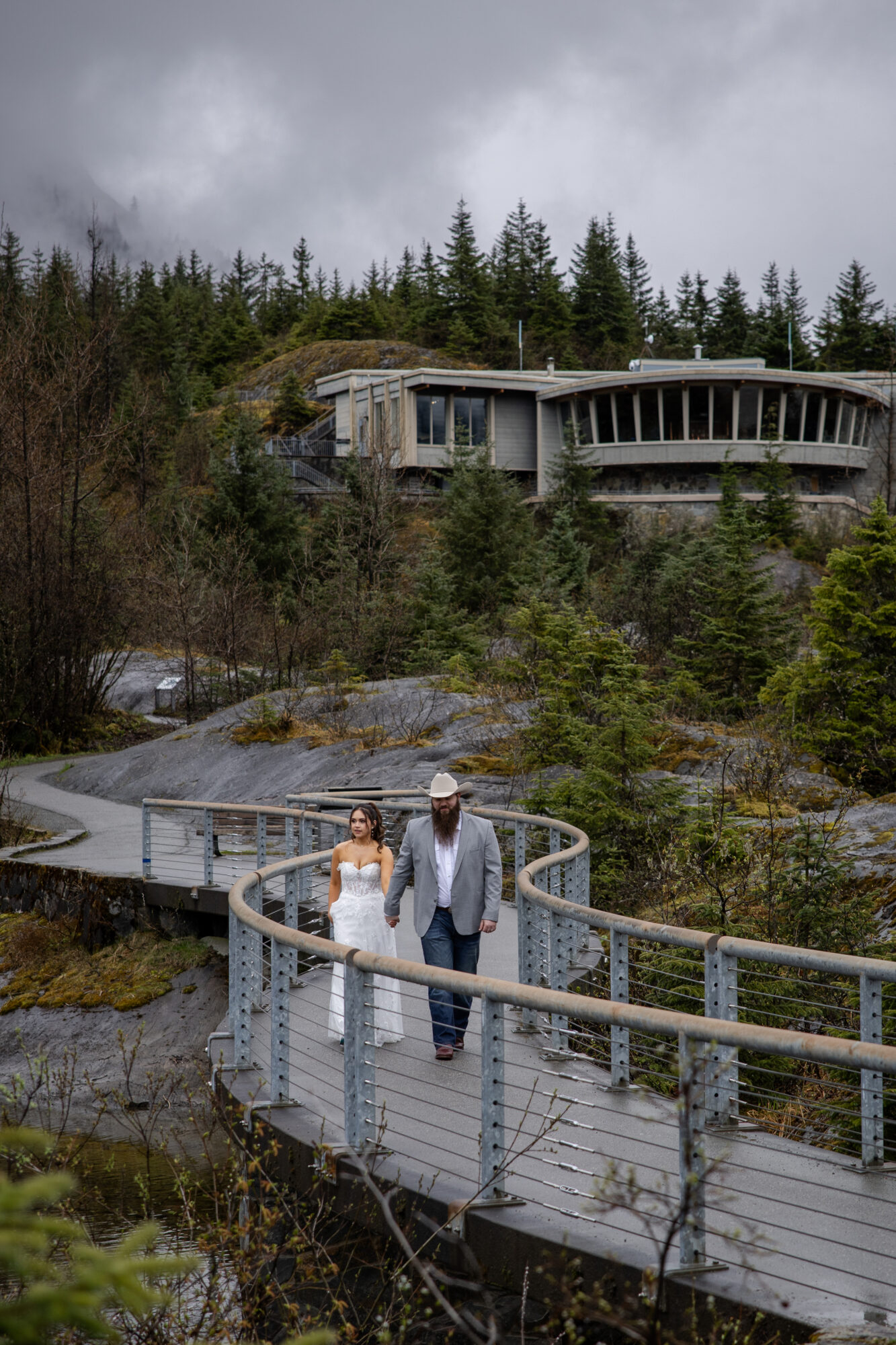 Couple walking along a scenic walkway near Mendenhall Glacier in Juneau, Alaska during an elopement.
