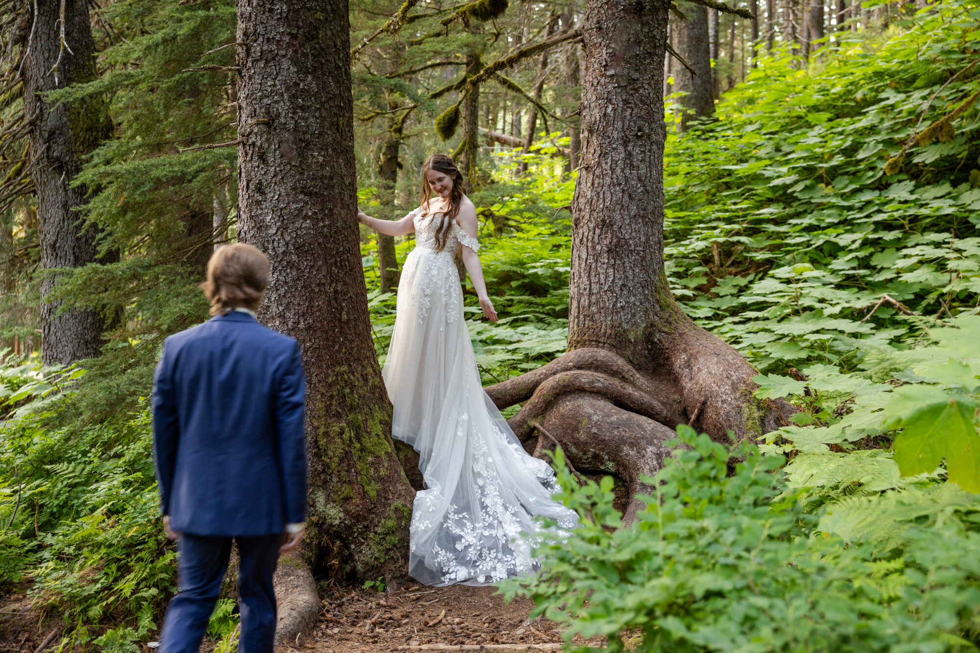 Couple exploring a dense forest in Girdwood, Alaska among towering trees during a quiet, nature-focused elopement.