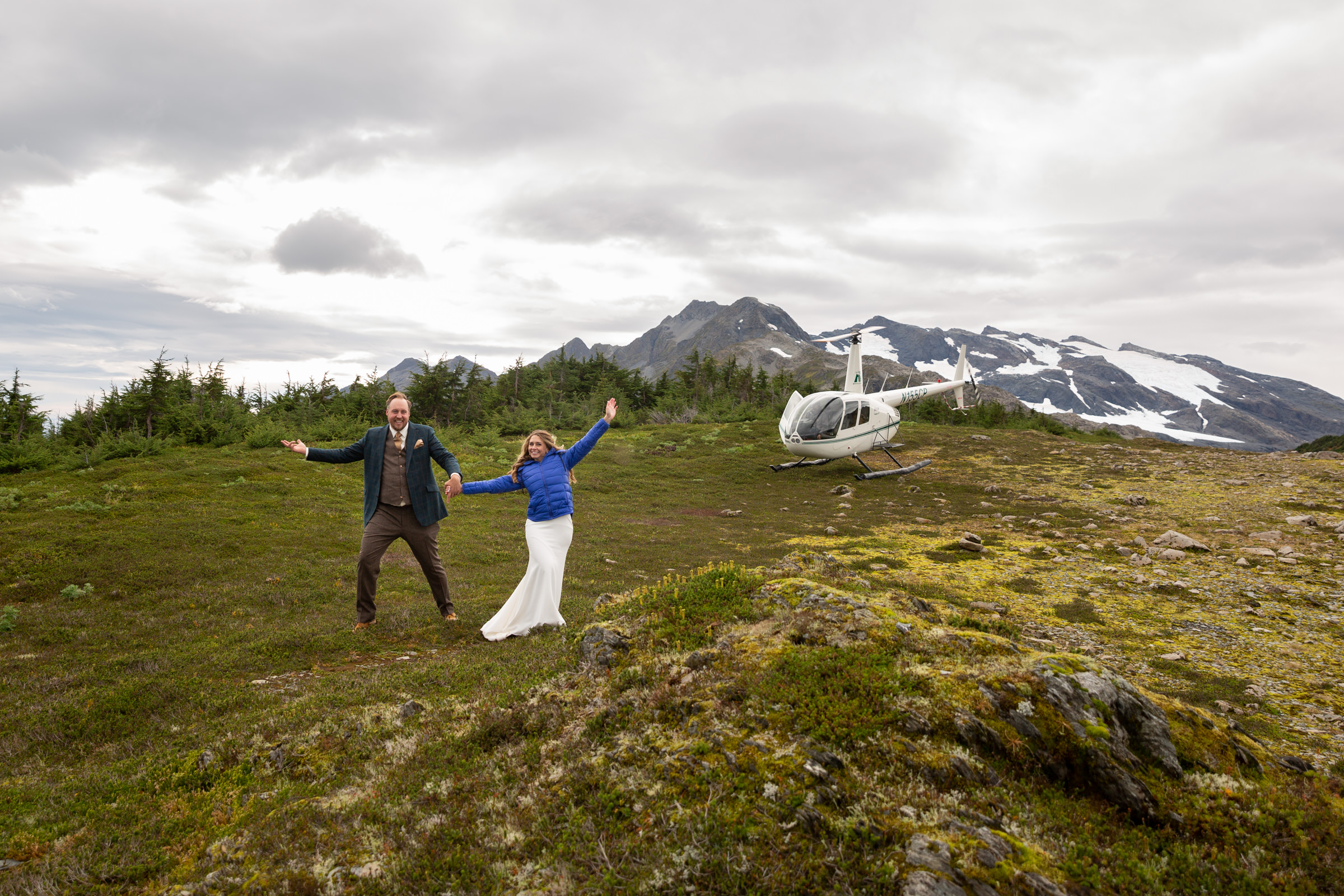 Newlyweds celebrating walking away from their helicopter Alaska elopement, surrounded by snow covered peaks.