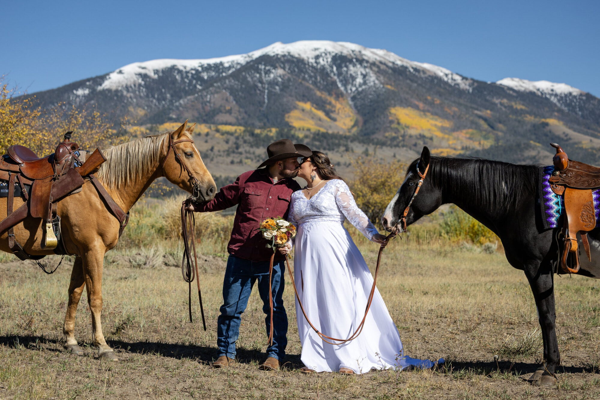 A Loveland Pass Elopement in Colorado: Horseback Riding and a Mountain Wedding | Scenic Vows Couple sharing a kiss with horses during their Loveland Pass elopement in Colorado mountains