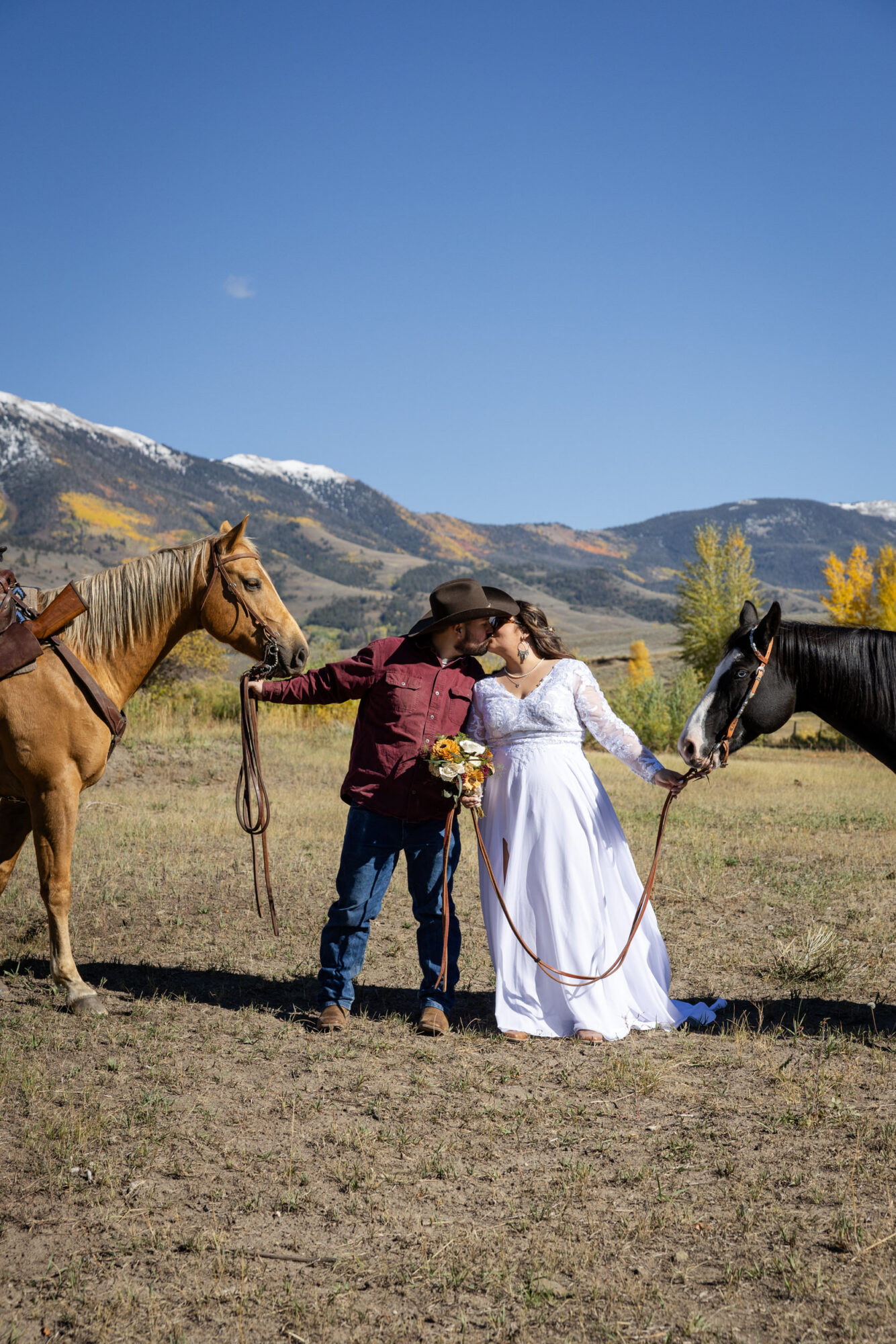 A Loveland Pass Elopement in Colorado: Horseback Riding and a Mountain Wedding | Scenic Vows Bride and groom kissing with horses during a Colorado mountain elopement near Loveland Pass