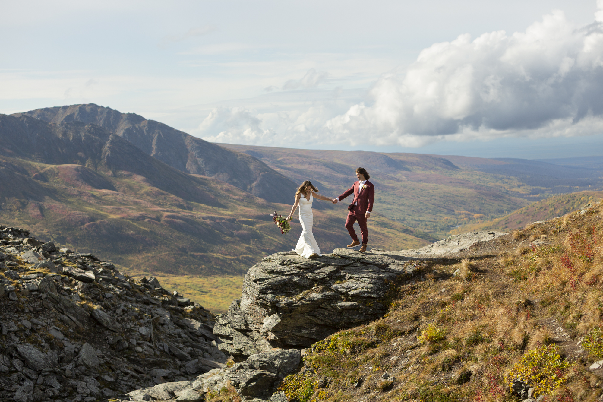 Couple standing on a rocky overlook in Hatcher Pass, Alaska with sweeping mountain and valley views during an adventurous elopement.