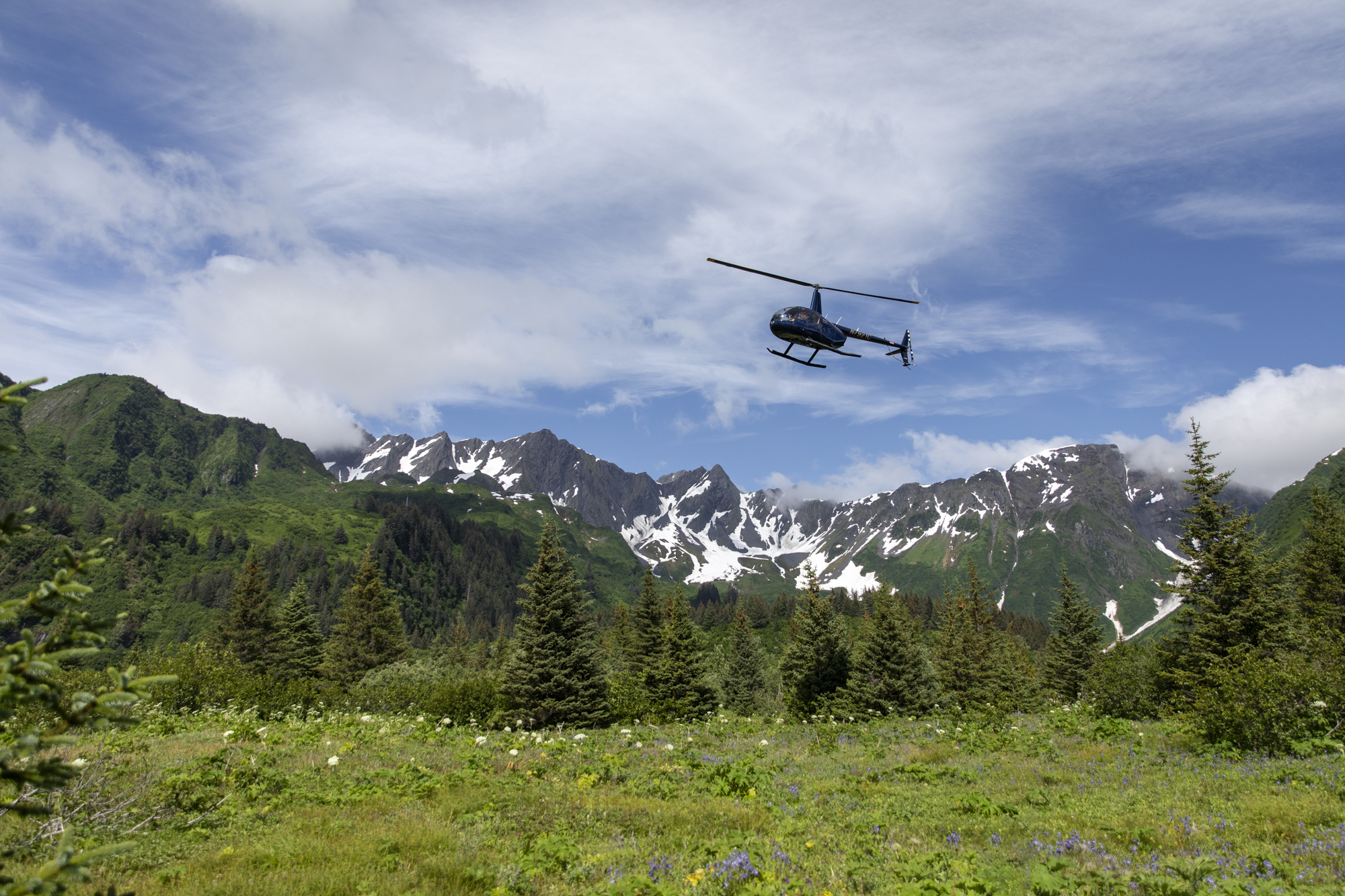Helicopter flying over alpine mountains on the Kenai Peninsula, Alaska, highlighting a remote adventure elopement experience.