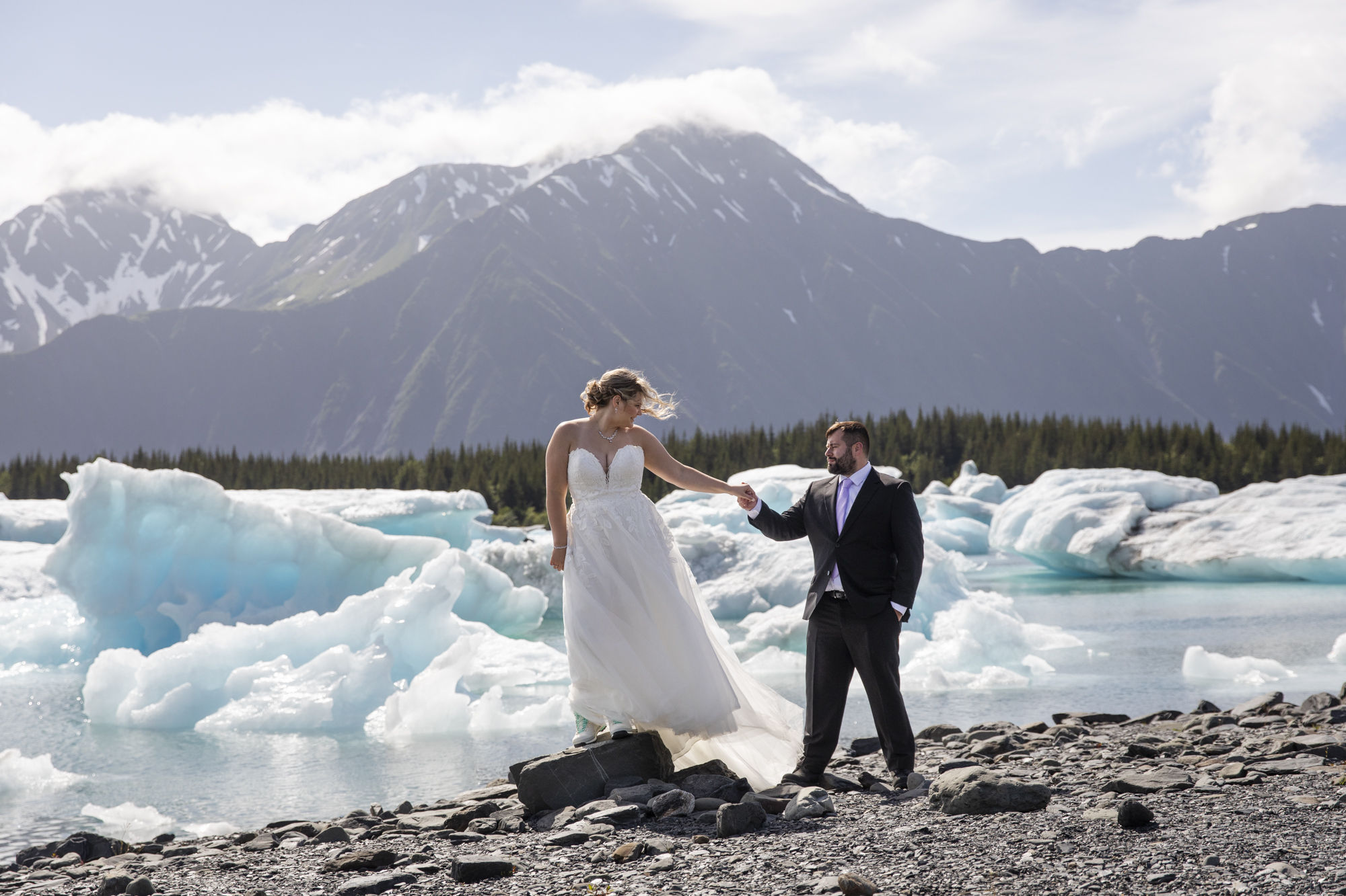 Couple standing beside blue glacier ice on the Kenai Peninsula, Alaska during a scenic glacier elopement.