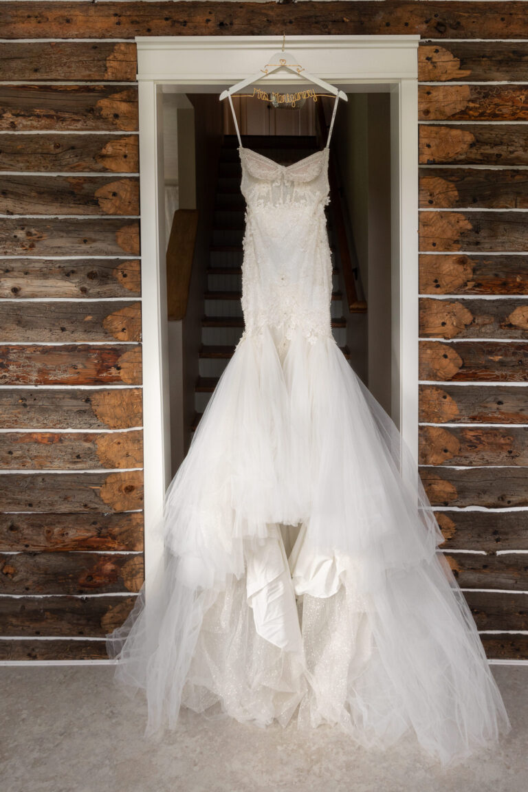 A wedding dress hangs on a hanger in a doorway on an Alaska elopement day.