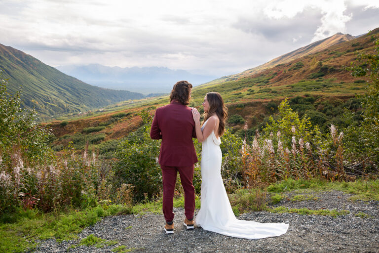 A bride and groom stand together while the Bride rests her left hand on the groom's right shoulder on their Hatcher Pass elopement day.