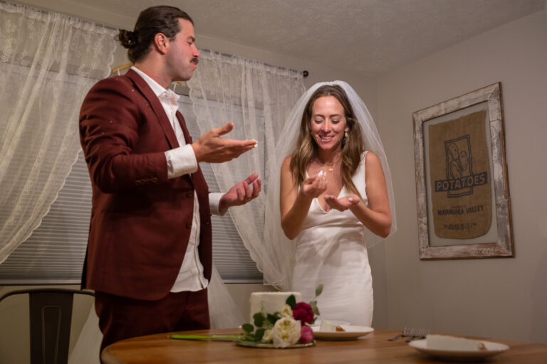 A bride and groom smash their wedding cake in each other's faces after their Alaska elopement day.