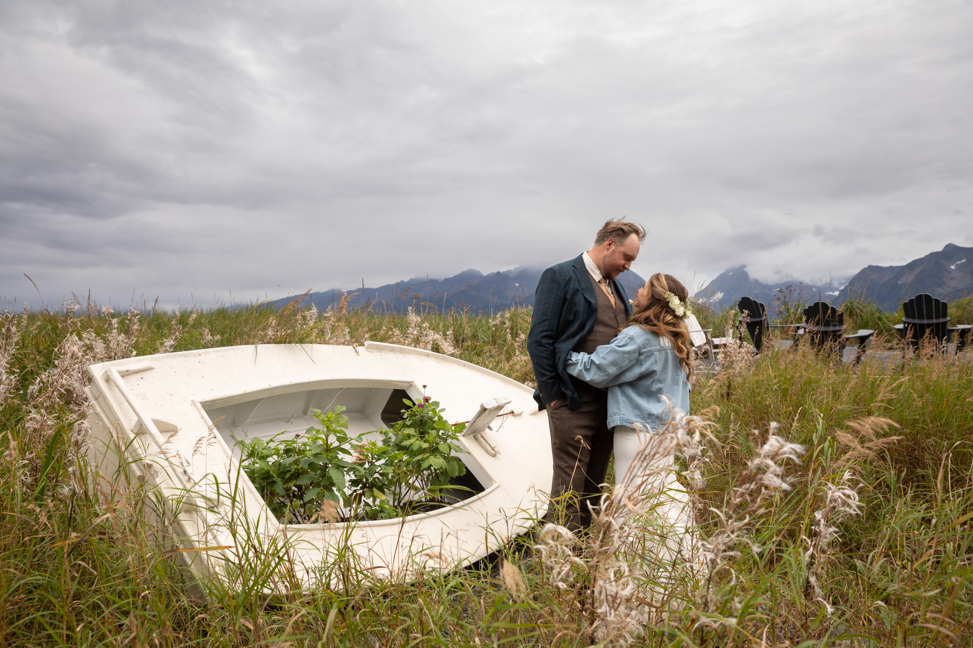 Couple embracing in a grassy coastal field near Seward, Alaska with mountains in the background during an intimate elopement.