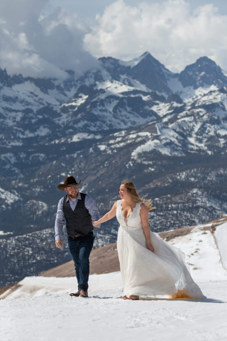 A bride and groom walk hand in hand up Mammoth Mountain on their elopement day.