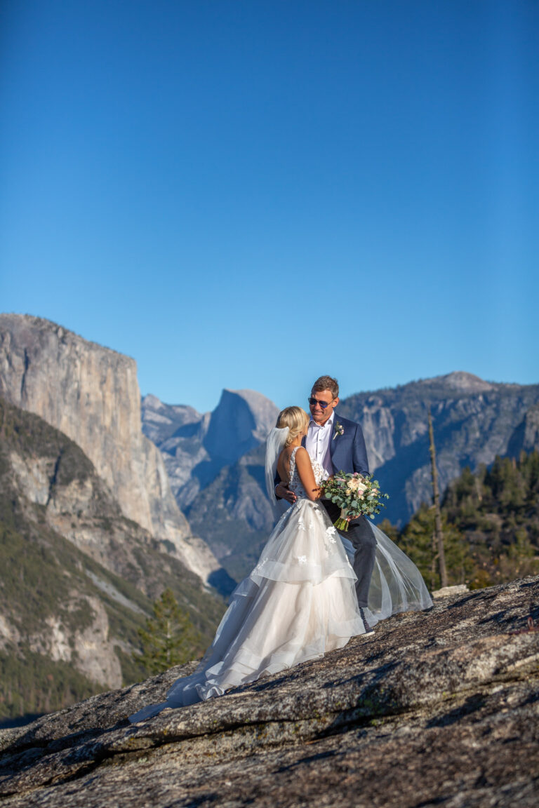 A bride and groom stand close to each other as the groom smiles down at his bride in Yosemite.