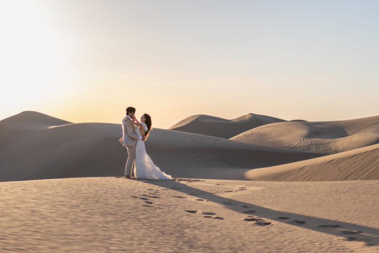 A bride and groom share their first dance on a giant sand dune in Glamis Sand Dunes California.