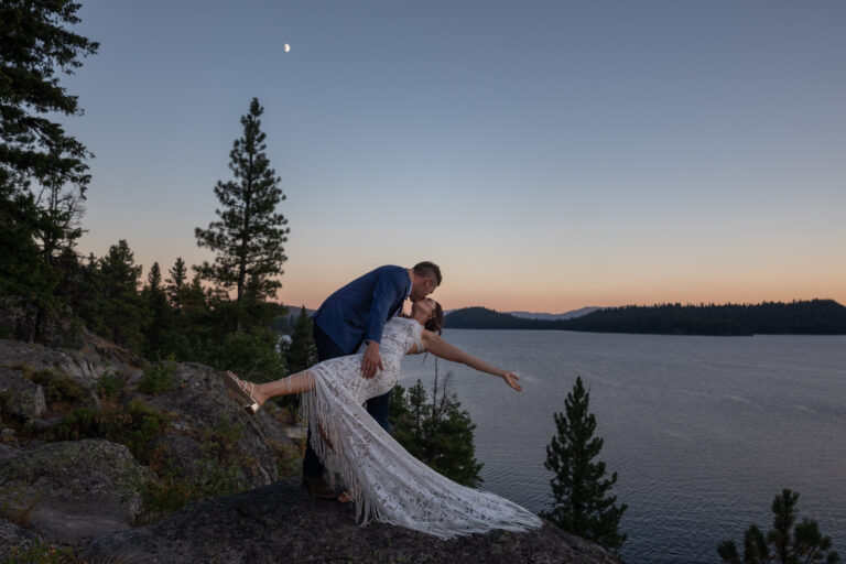 A groom dips his bride as they share a kiss in Idaho on their wedding day