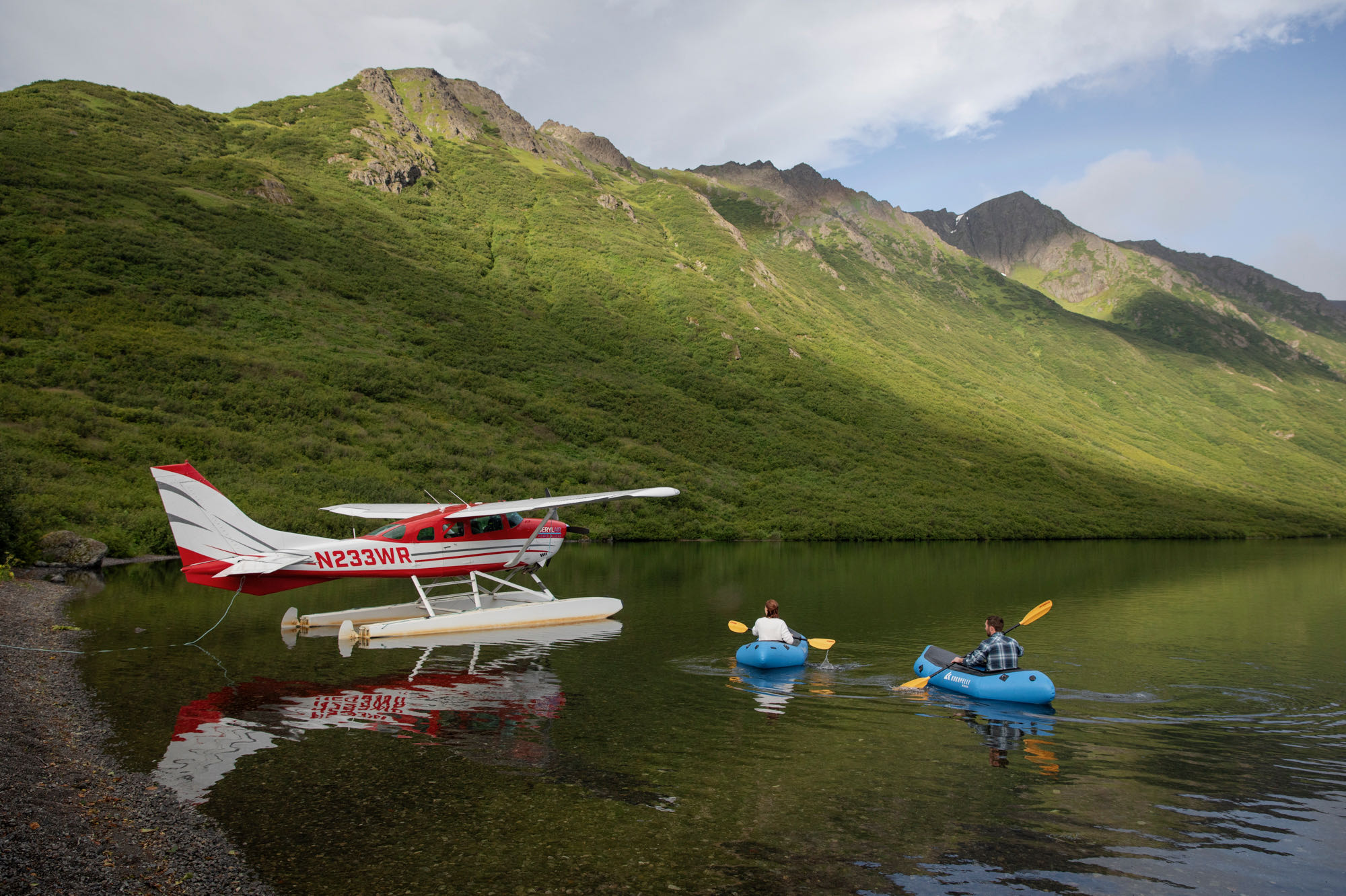 A couple paddles around a lake in Alaska on their elopement day, while a float plane is anchored on the water next to them.