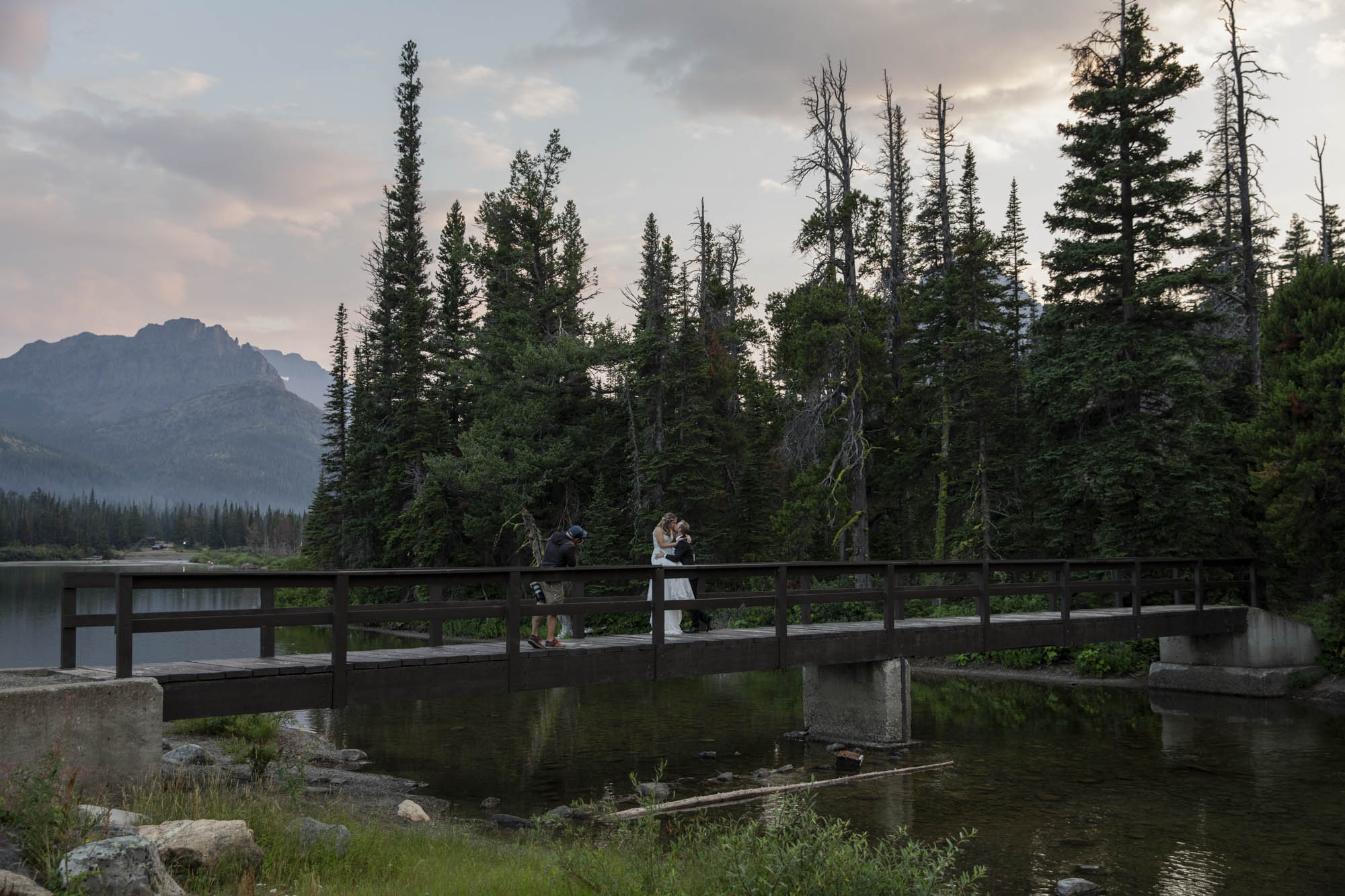 A couple wearing wedding clothes, kiss on a bridge after choosing the right elopement photographer for their wedding day.