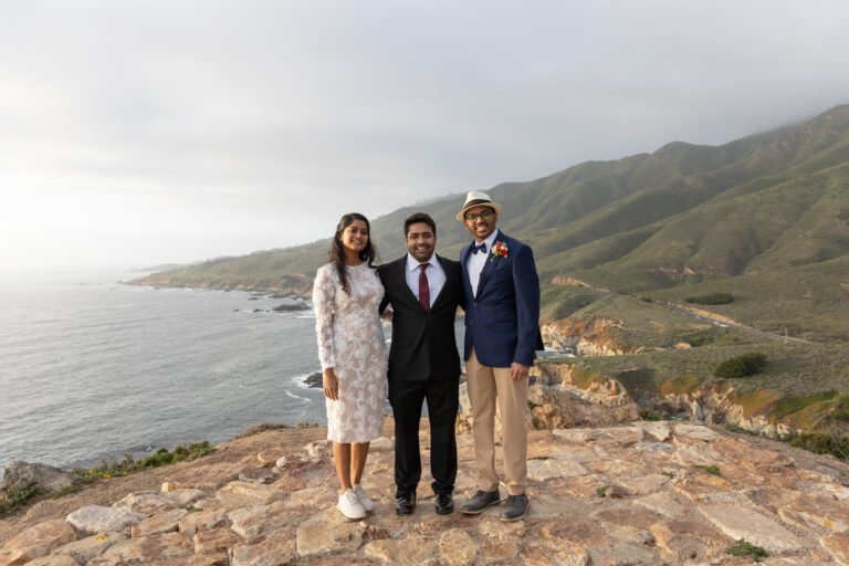 The bride, groom, and their best friend the officiant smile after their cliffside wedding ceremony.