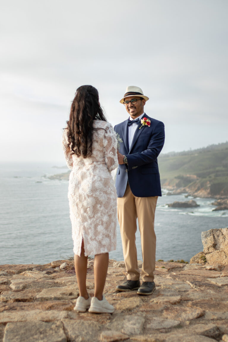 A bride and groom hold hands during their cliffside wedding.