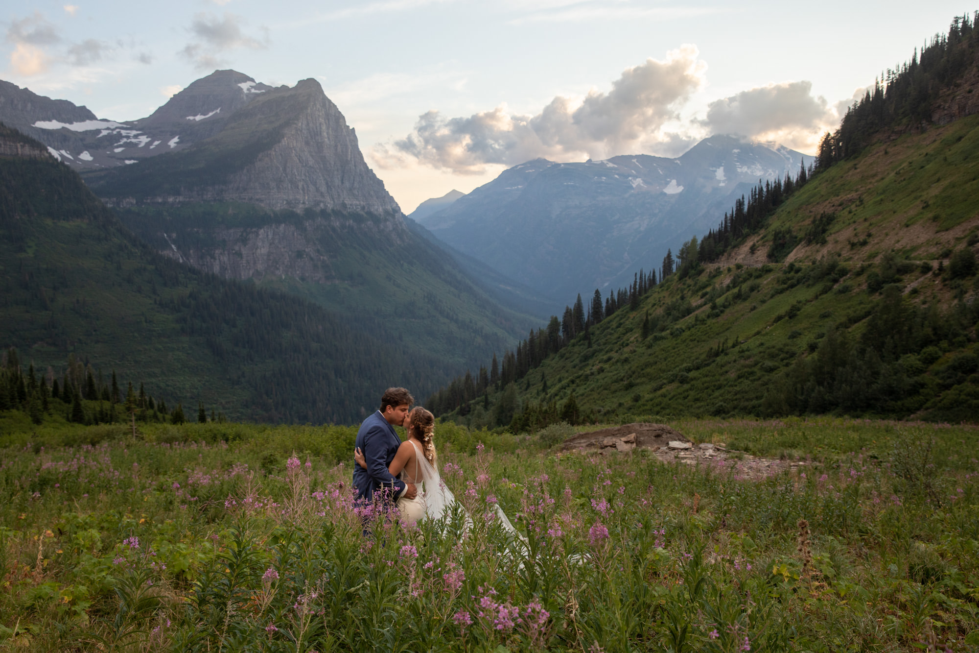 A couple stand in a meadow kissing in our favorite place to elope in Montana, Glacier National Park.