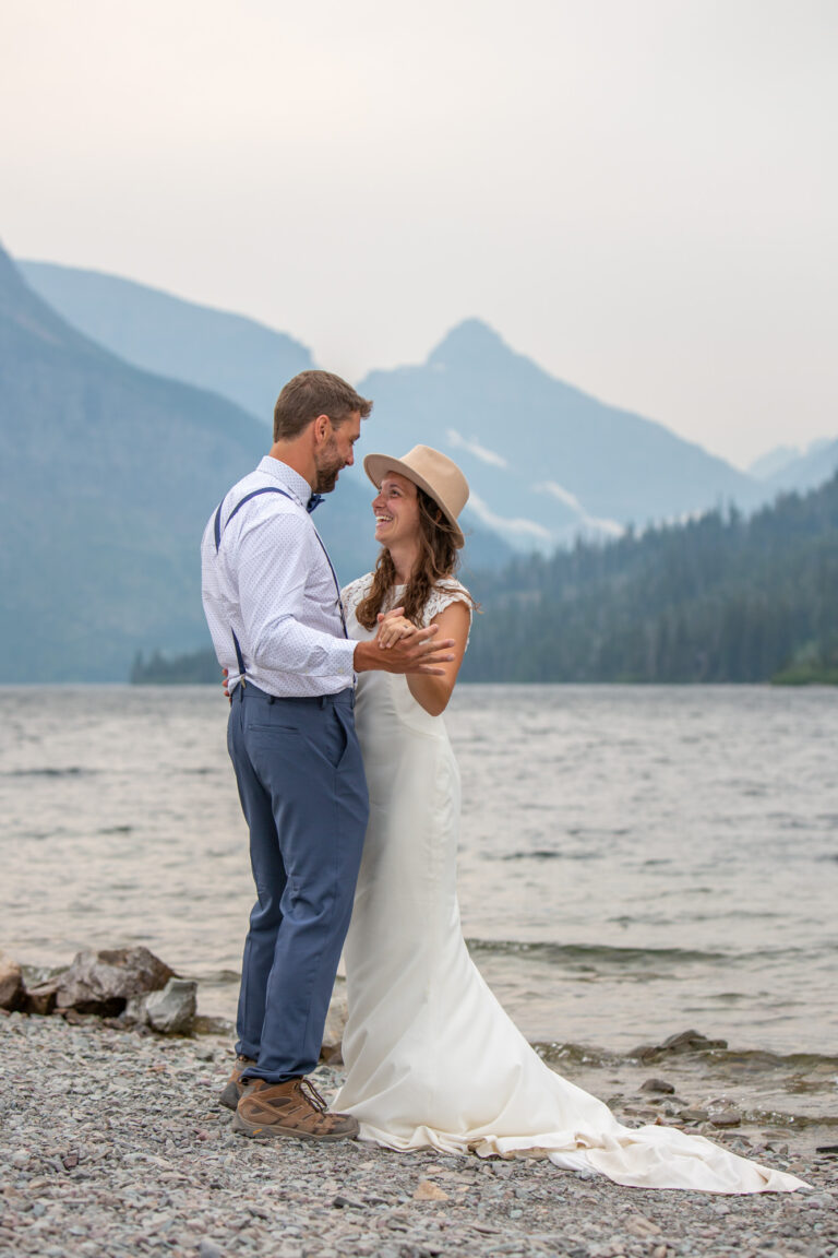 A bride and groom dance on the shore of a lake in Montana.