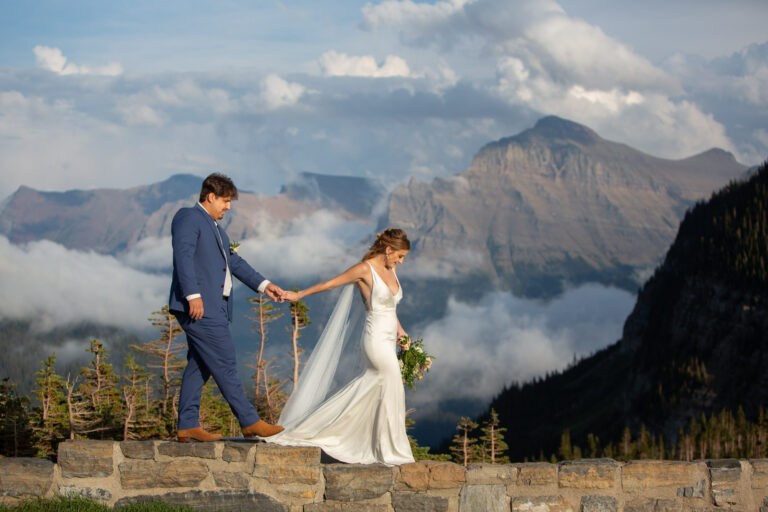 A bride leads her groom along a rock wall on their wedding day in Montana.