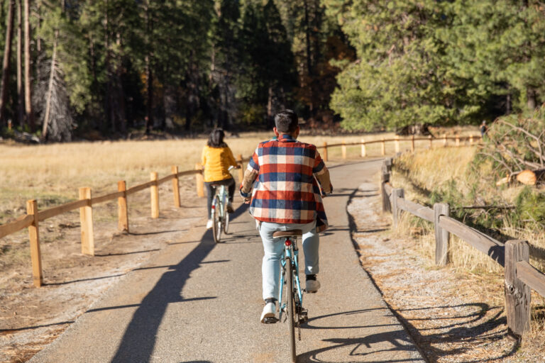 A couple ride their bikes through Yosemite National Park during their engagement session.