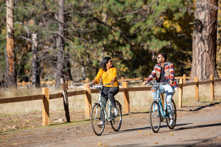 A couple ride bikes along a path in Yosemite National Park