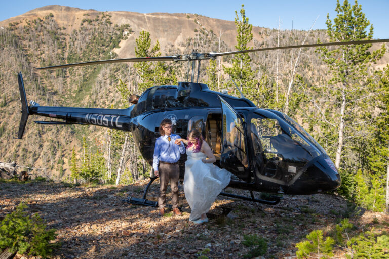 A groom helps his bride out of a helicopter on their elopement day in Montana.