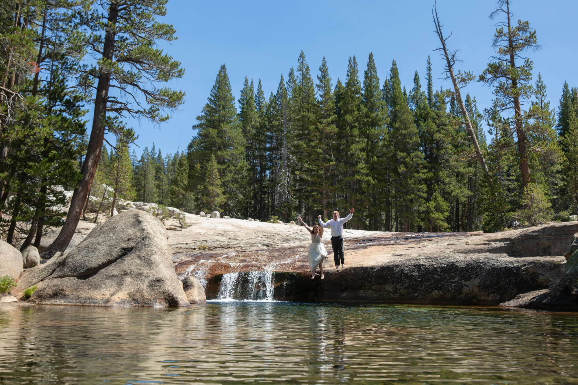 A bride and groom just off a rock into a lake in Yosemite on their elopement day.