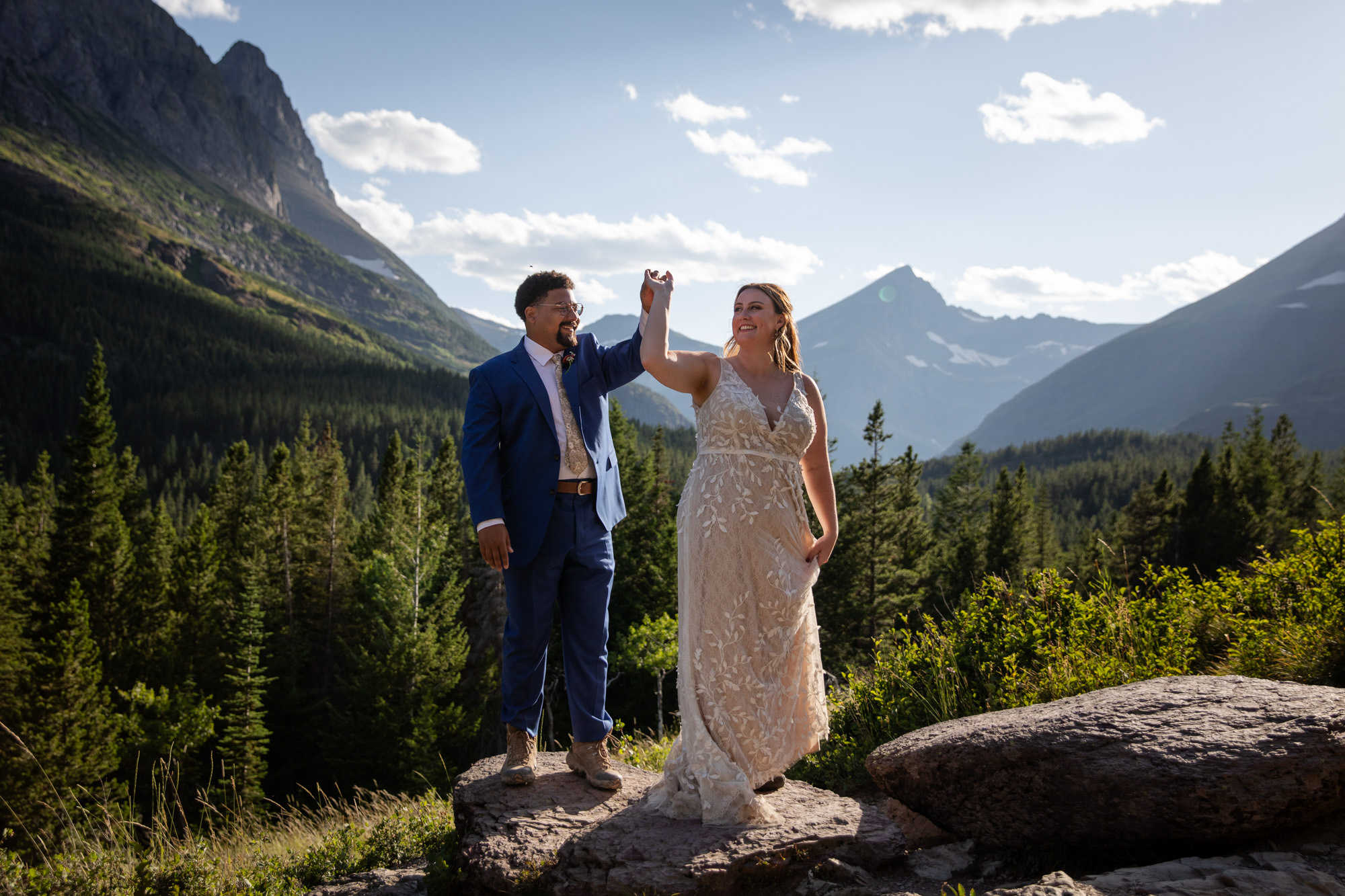 A bride and groom dance on a rock after eloping in Glacier national park.