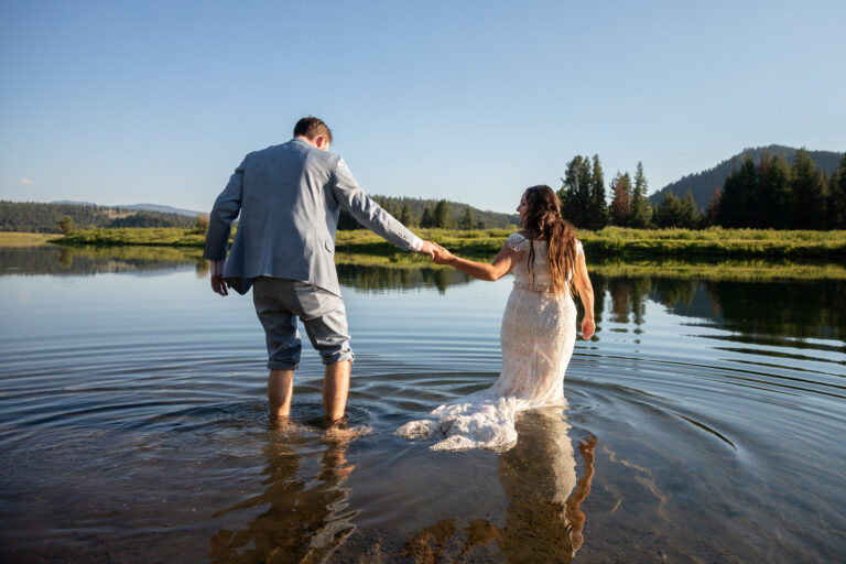 A bride leads her groom into a river on their wedding day after eloping in Grand Teton.
