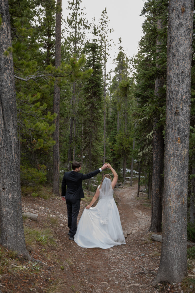 A newly wed couple stands dancing in a forest in Grand Teton National Park