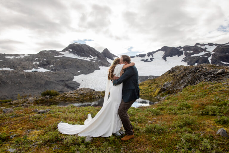 Bride and groom hug after their elopement ceremony with snowcapped mountains in the background.