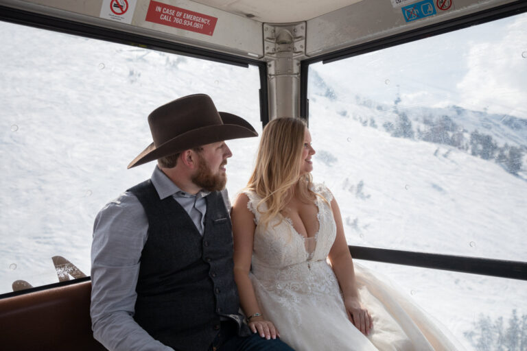 A bride and groom sit in a gondola riding down the mountain in Mammoth CA.