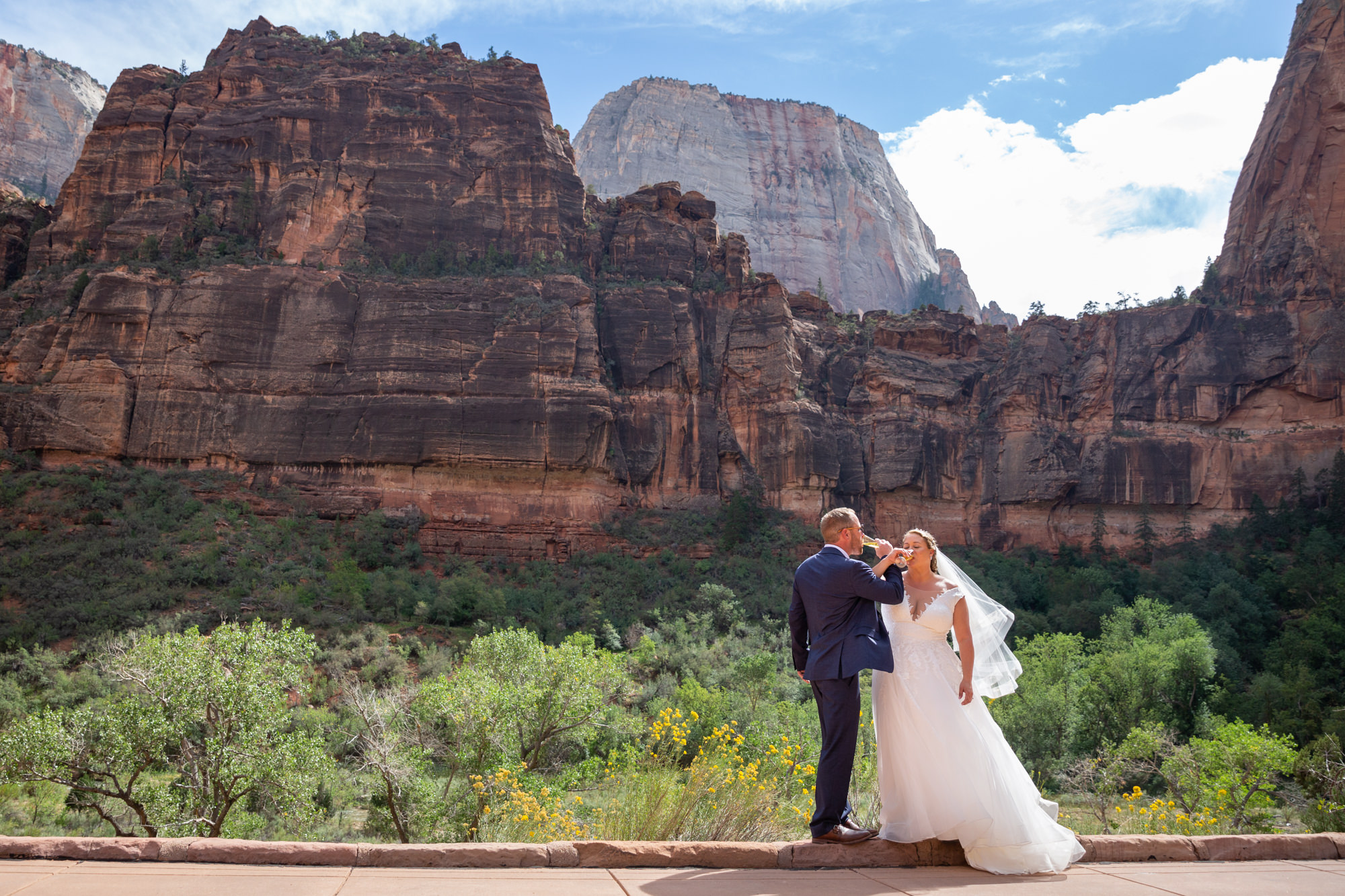 A bride and groom sip champagne on their elopement day after figuring out how to elope in Zion National Park.