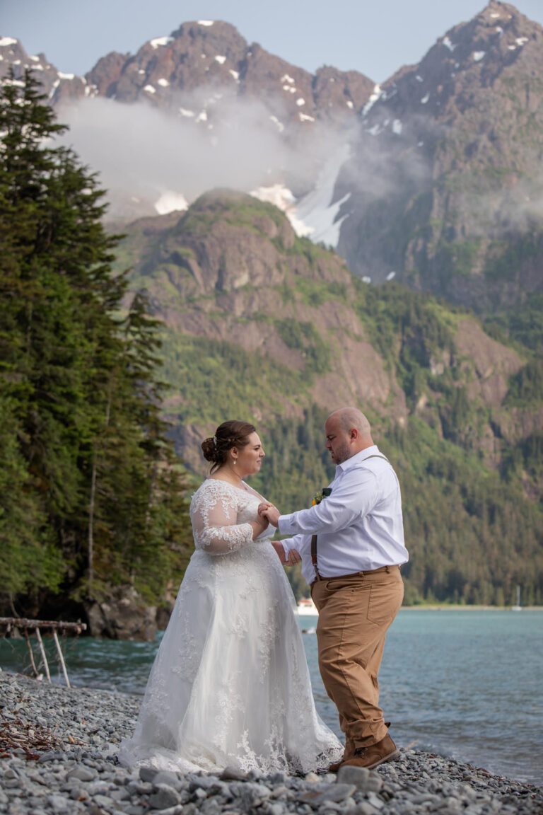 A bride and groom dance on a rocky beach in Alaska after figuring out how to elope.