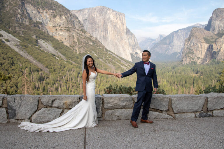 A groom leads his bride along a rock path in Yosemite.