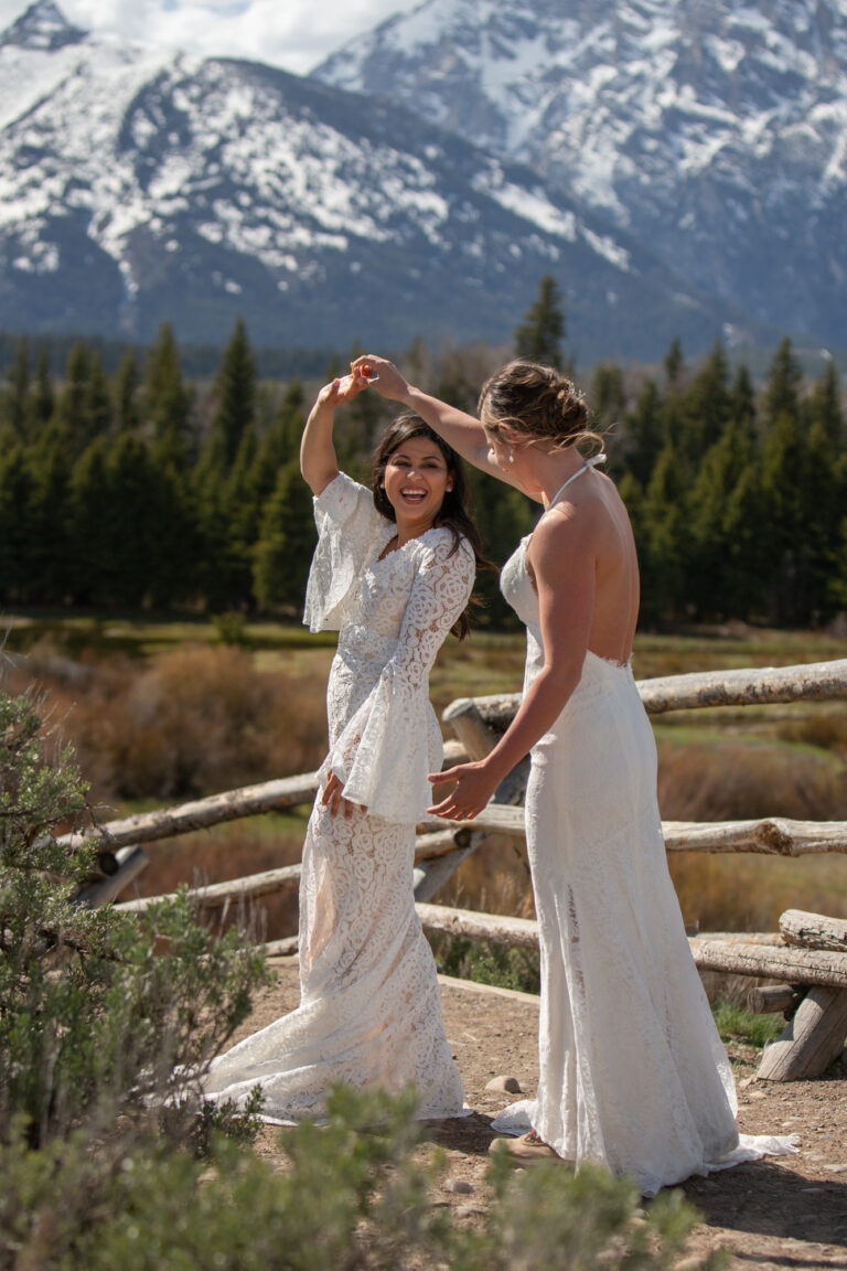 A bride twirls her bride, admiring her wedding dress after their first look in Grand Teton National park.