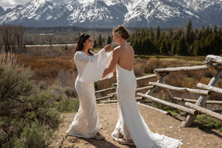 Brides reach for each other to embrace after seeing each other all dressed up for the first time on their wedding day.