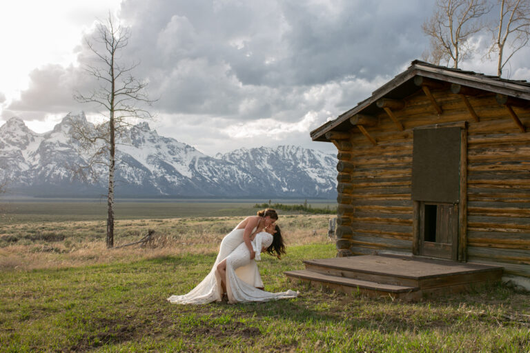 Two brides share a dip and deep kiss while eloping in Grand Teton National Park.
