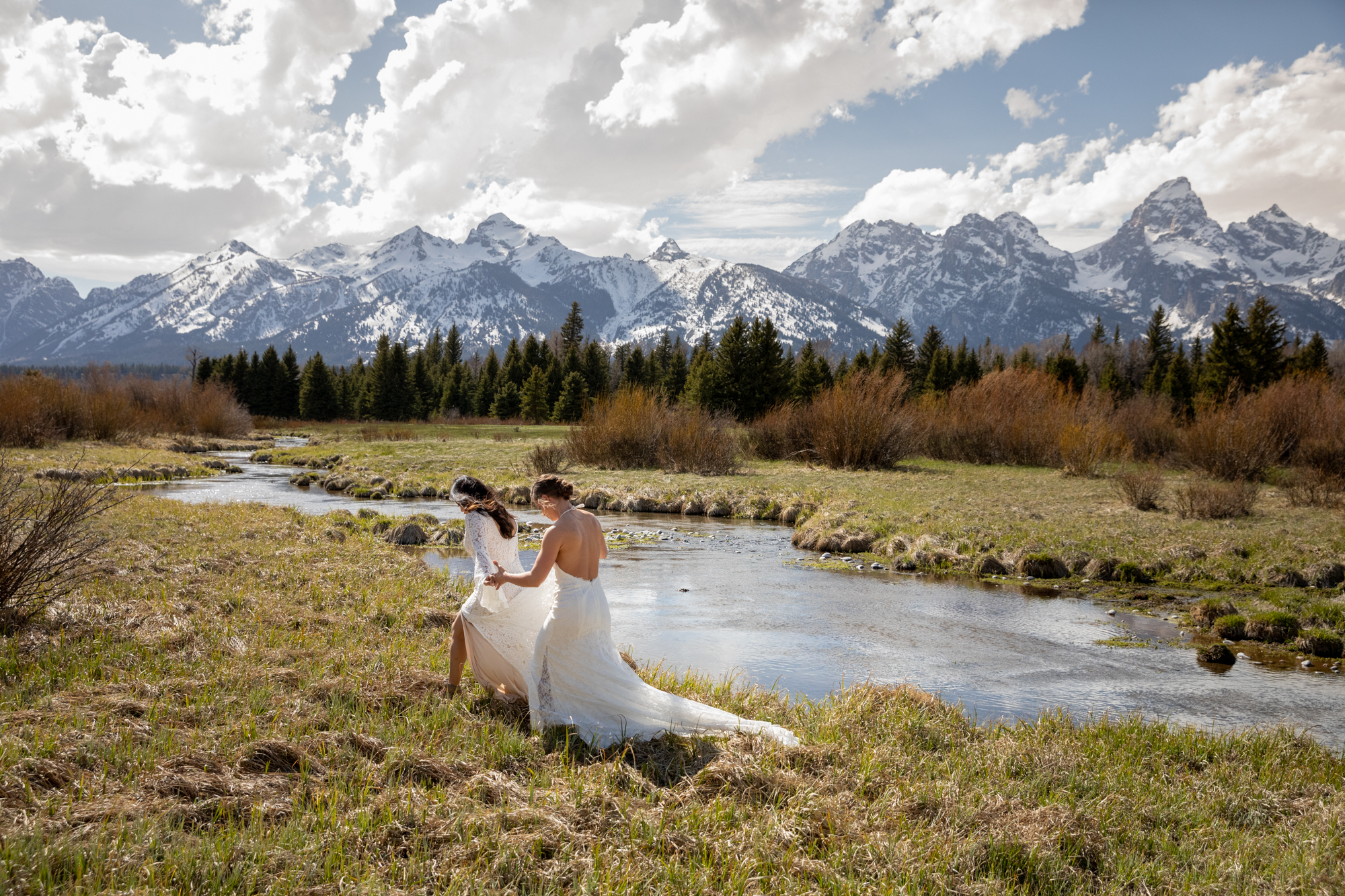 Two brides walk along the Snake River on their Jackson Hole elopement day.