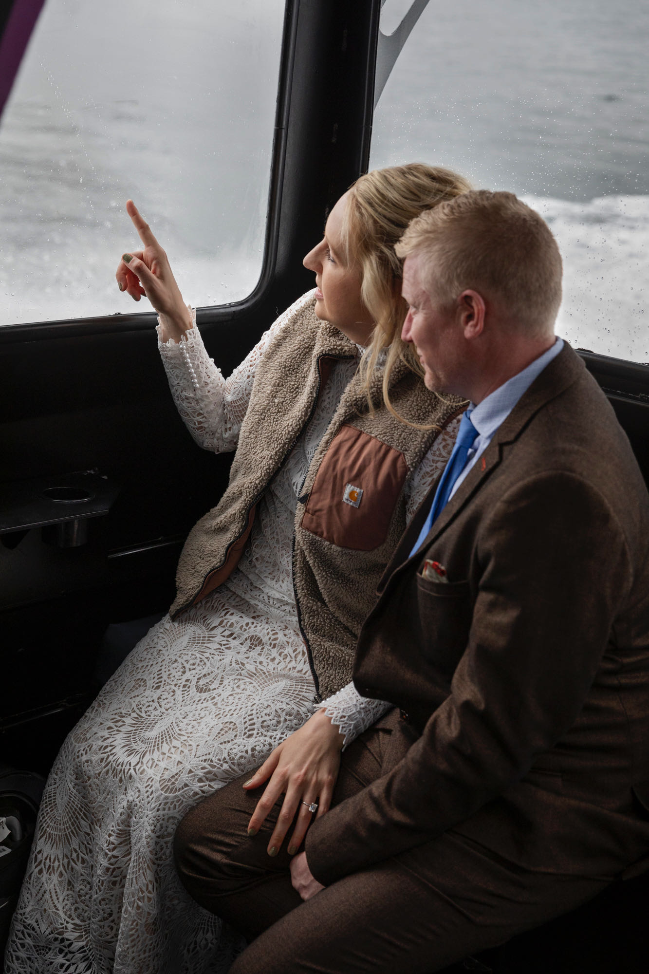 A bride points out the window of a boat as they cruise through Kachemak bay.