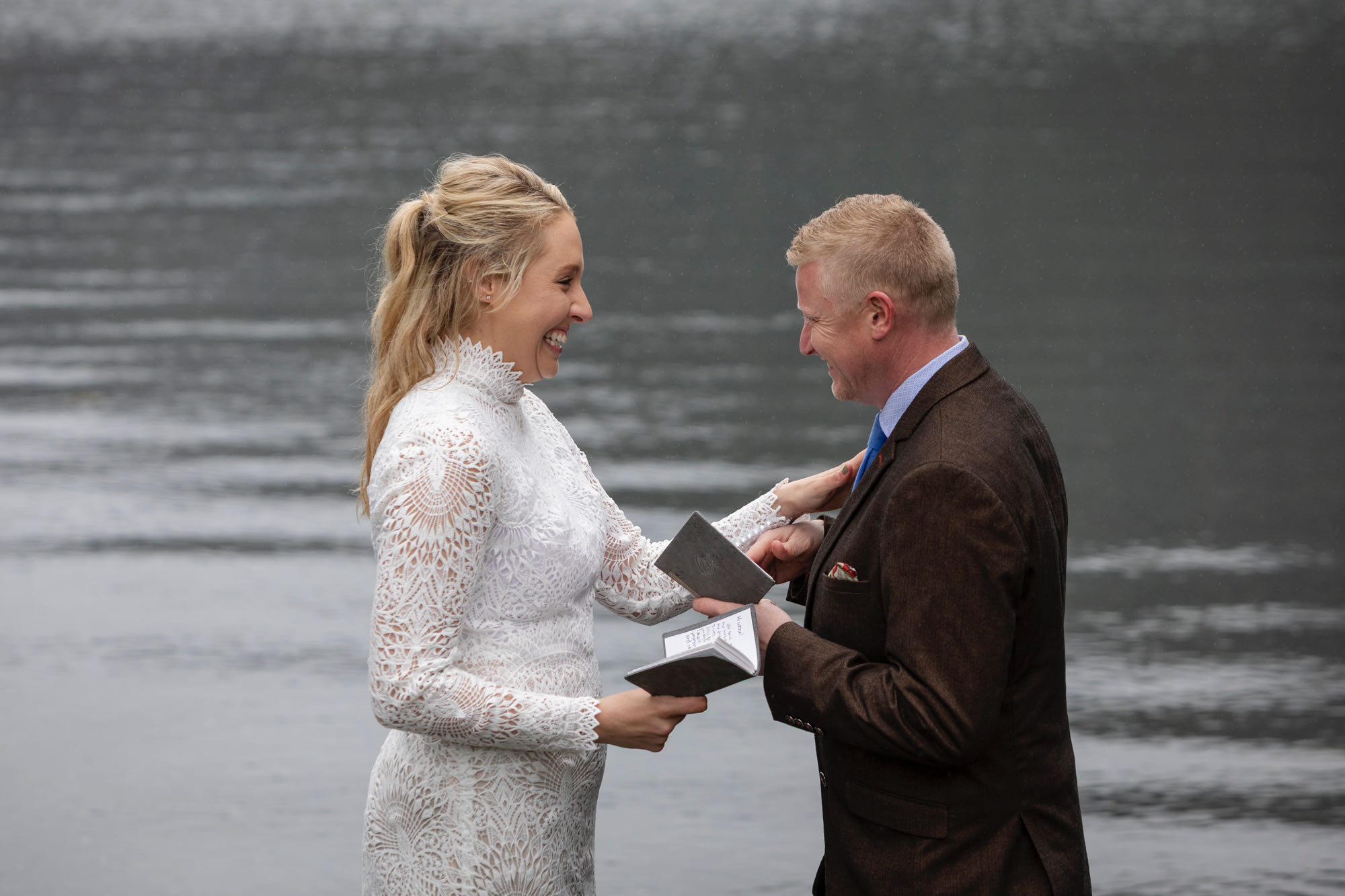 Bride smiling and reading vows during rainy Kachemak Bay elopement in Homer Alaska