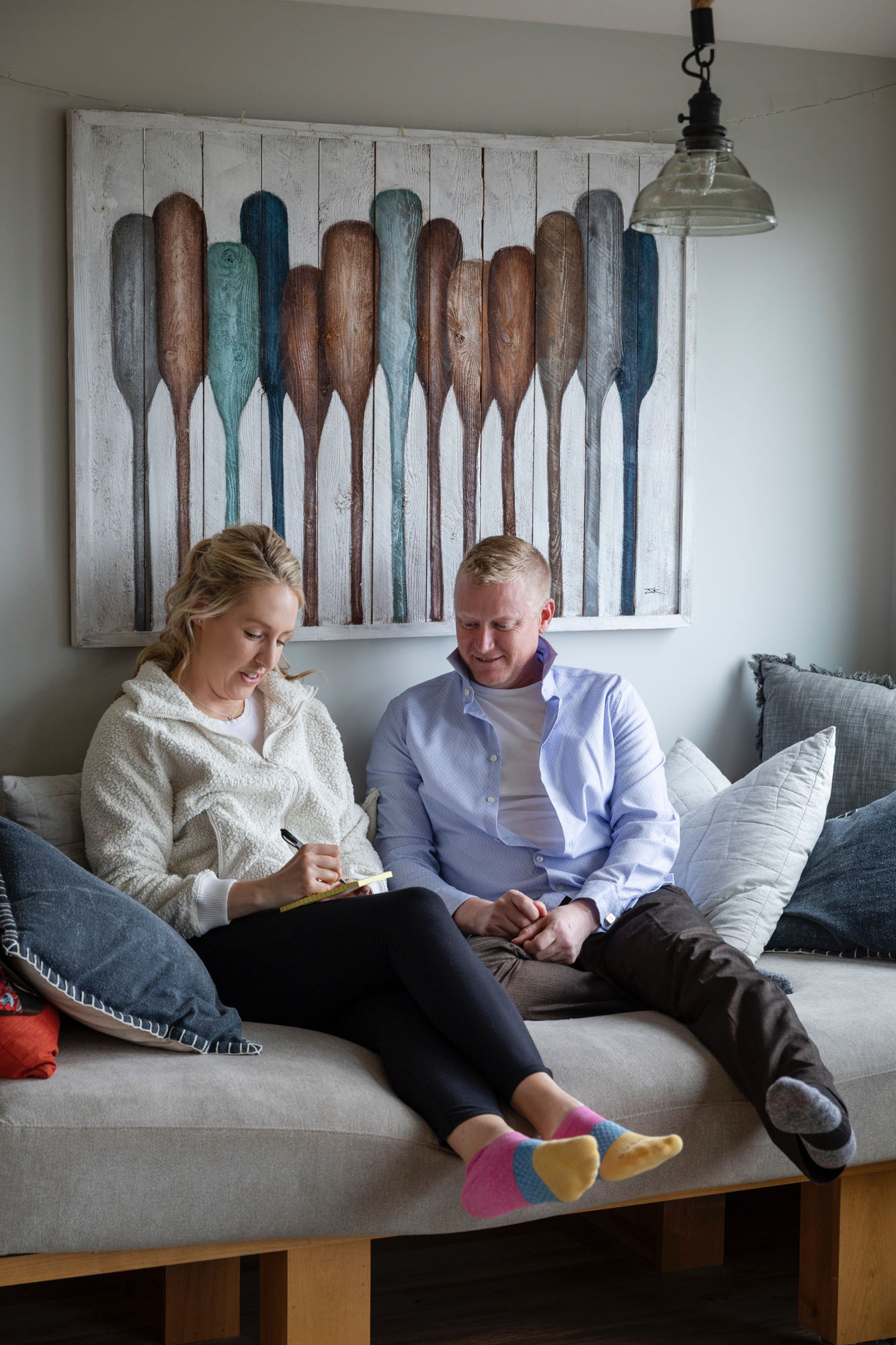 A bride and groom sit playing tic-tac-toe together on a couch before their elopement ceremony.