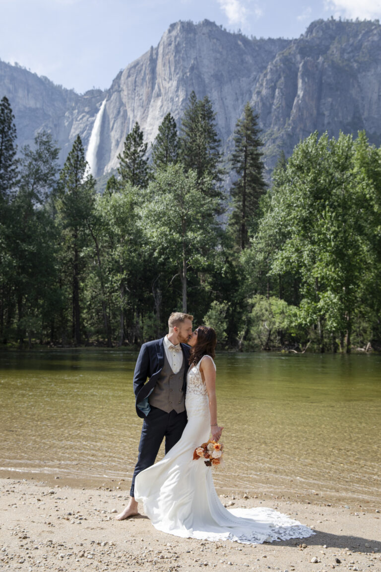 10 Breathtaking Places in California to Elope | Scenic Vows A bride and groom kiss while standing on a beach next to a river after getting married in on of the best places in California to elope.