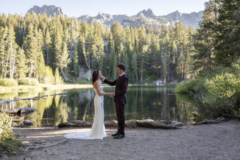 10 Breathtaking Places in California to Elope | Scenic Vows A groom reaches up to caress his bride's check while they stand next to a lake in the mountains.