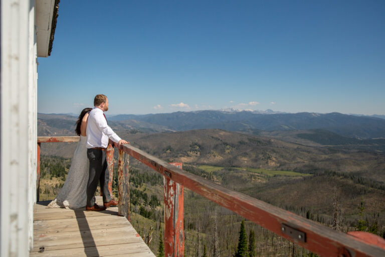 A bride and groom stand next to each other looking at the Stanley Idaho views on their elopement day.