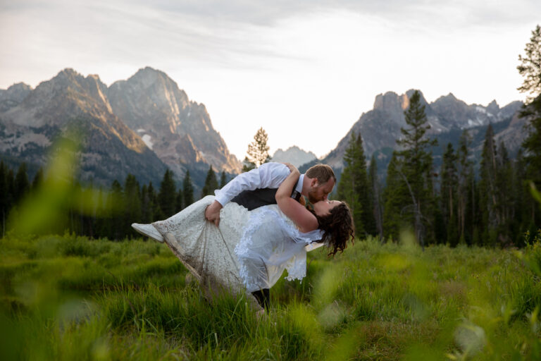 A groom dips his bride and kisses her deeply after their elopement.