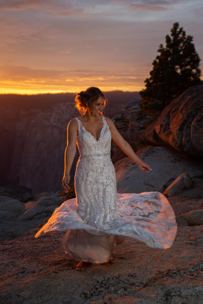 A bride twirls around in her dress as the sunsets behind her on her wedding day.