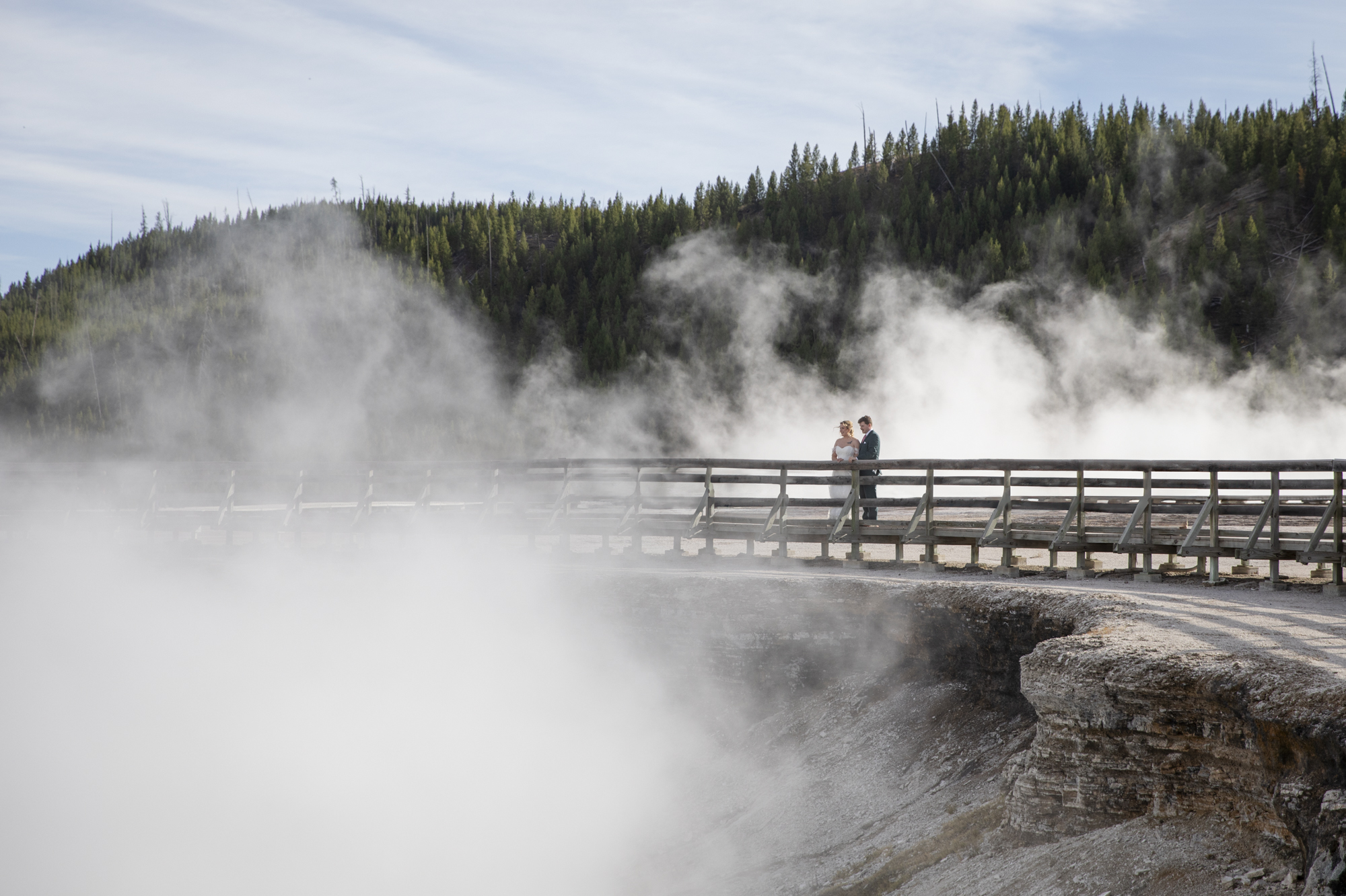 8 Incredible Places to Elope in Wyoming | Scenic Vows Newlyweds exploring a steaming geothermal area during their Yellowstone National Park elopement