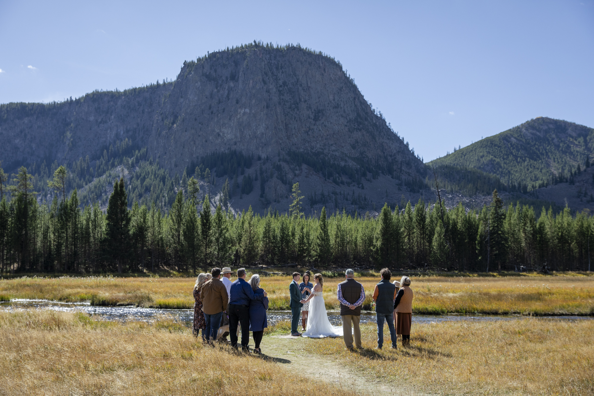8 Incredible Places to Elope in Wyoming | Scenic Vows Couple having an intimate wedding ceremony beside a river in Yellowstone National Park