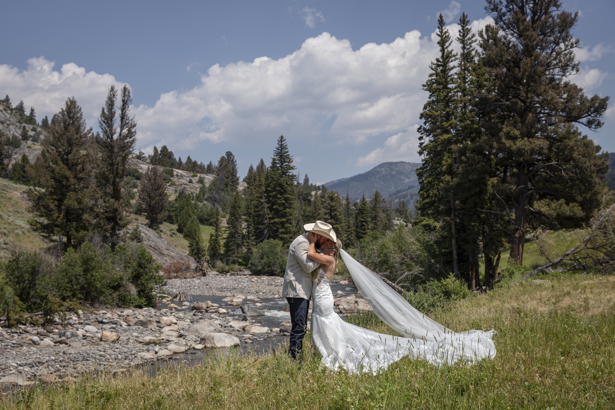 8 Incredible Places to Elope in Wyoming | Scenic Vows Bride and groom kissing beside a mountain stream at one of the best places to elope in Wyoming